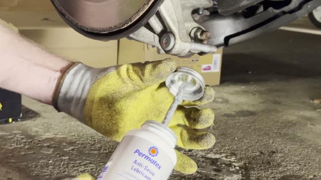 Applying Permatex anti-seize to the lower shock mounting stud