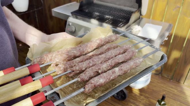 Raw kebabs on metal skewers, ready for the grill