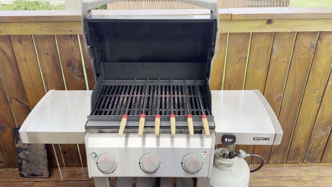 Weber Spirit II grill open on the deck, set up for a skewer rack