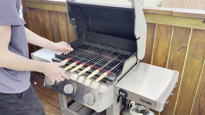 Skewers resting on the steel angle rack inside the grill