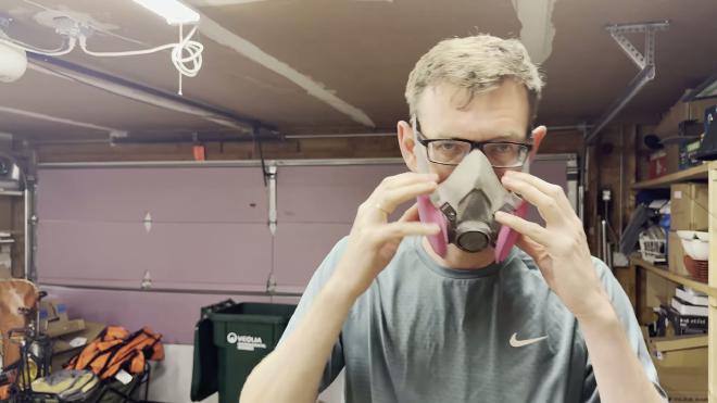 Wearing a 3M respirator before applying insecticide dust