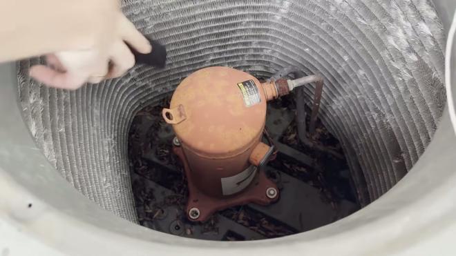 Vacuuming dirt and debris from the bottom of the outdoor AC unit