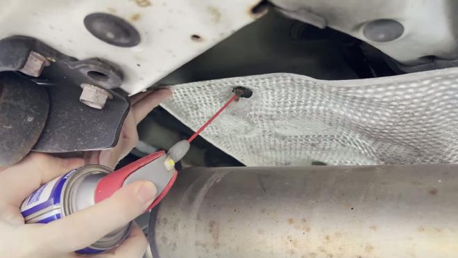 Spraying WD-40 on a rusty Toyota RAV4 heat shield mounting nut