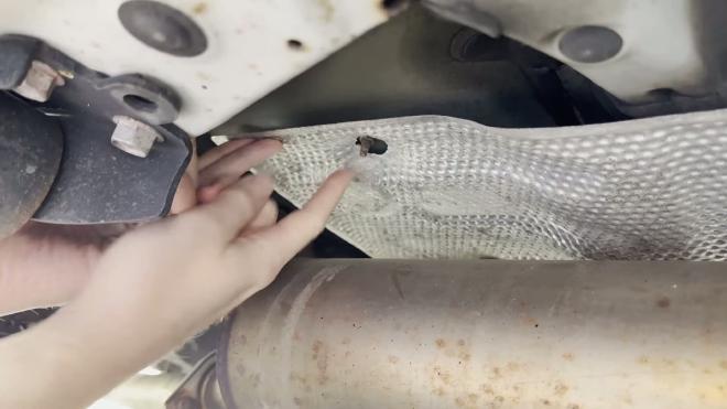 Damaged Toyota RAV4 exhaust heat shield mounting hole with a rusty stud