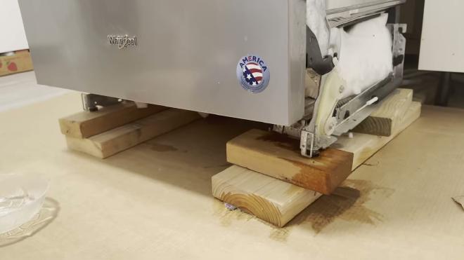 Whirlpool dishwasher pulled out and supported on 2x4s